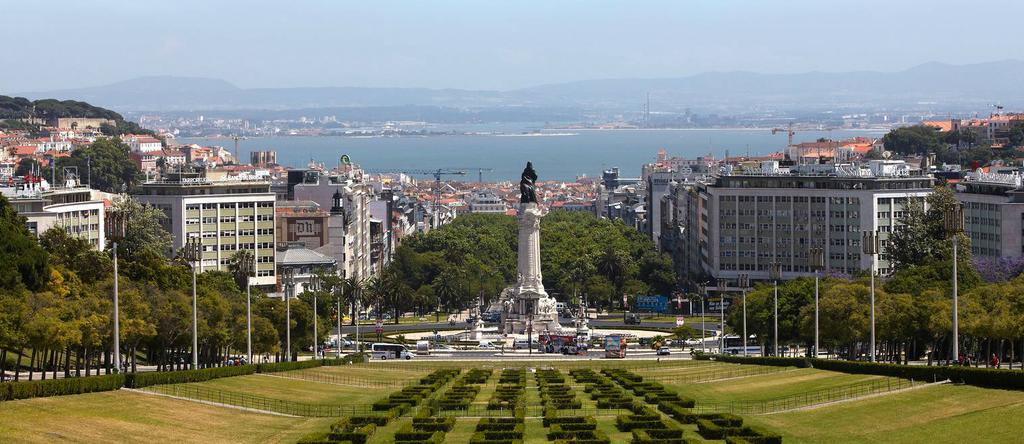 A view of the city from above shows a park, a statue and a large body of water.