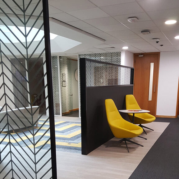 A room with two yellow chairs and a black divider